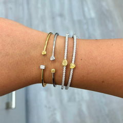 Light yellow radiant cut and F color heart shaped diamonds in a VS clarity white gold bezel cuff.