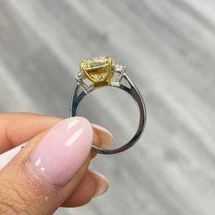 Unique engagement ring with an elongated yellow center diamond and two white diamonds on the sides.