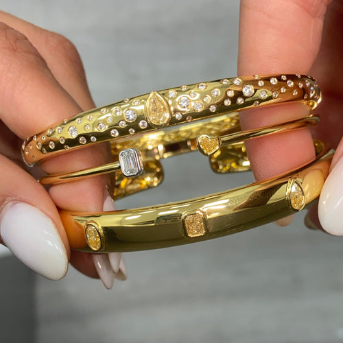 Unique bezel cuff bracelet with trio of yellow diamonds in radiant, oval, and pear shapes on a wide bangle.