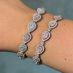 Delicate bracelet with pink and silver teardrop-shaped stones on a wrist against a blurred background