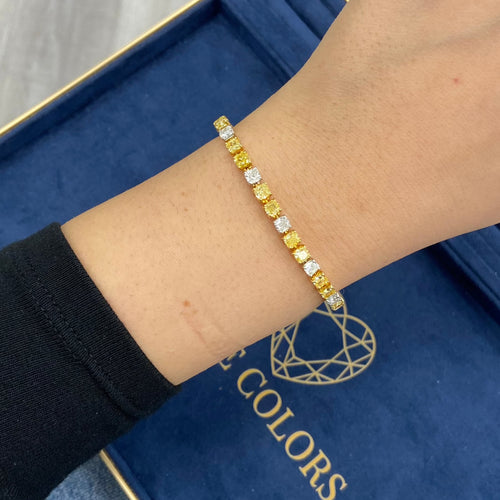 Fancy tennis bracelet with alternating yellow and white cushion cut diamonds.