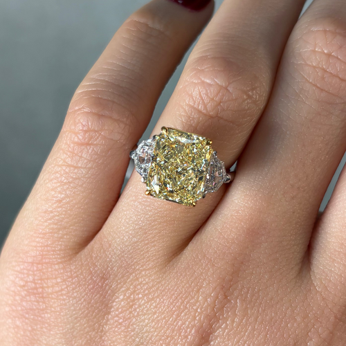 Close-up of a hand wearing a diamond ring with a yellow diamond center stone.