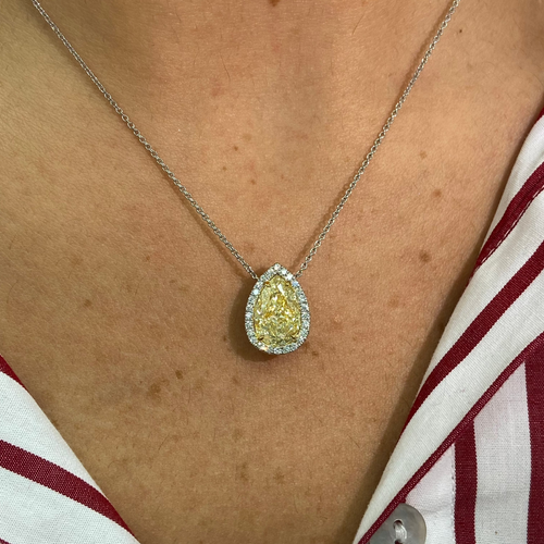 Pear shape yellow diamond with white halo diamonds and a VVS2 clarity.