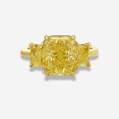 Yellow diamond three stone ring on a white background