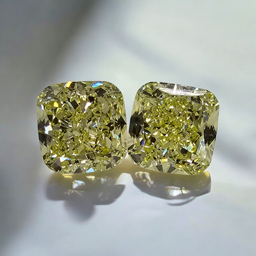 Unique matched pair of natural fancy light yellow cushion cut diamonds.