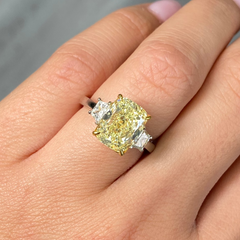 Unique engagement ring with an elongated yellow center diamond and two white diamonds on the sides.
