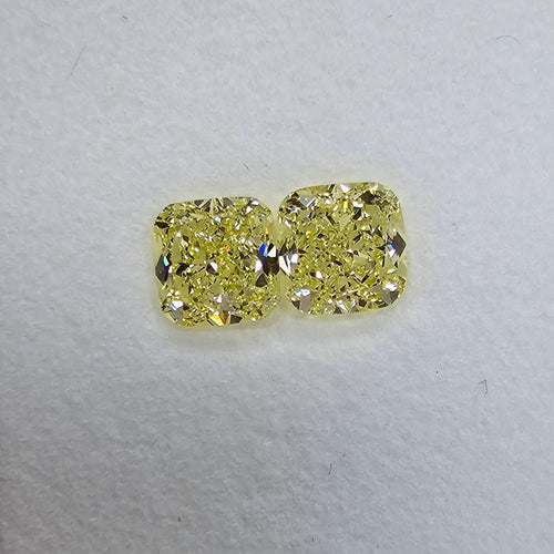 Unique matched pair of natural fancy light yellow cushion cut diamonds.