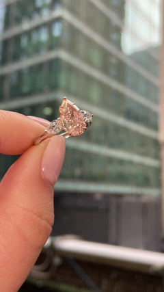 Elegant pink pear-shaped diamond engagement ring with VS1 clarity and sparkling side stones.