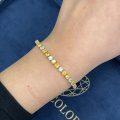 Fancy tennis bracelet with alternating yellow and white cushion cut diamonds.