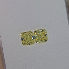 Unique matched pair of natural fancy light yellow cushion cut diamonds.