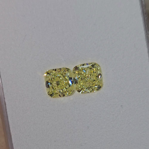 Unique matched pair of natural fancy light yellow cushion cut diamonds.
