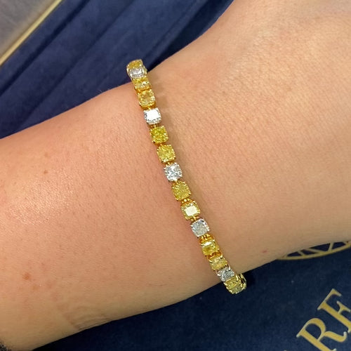 Fancy tennis bracelet with alternating yellow and white cushion cut diamonds.