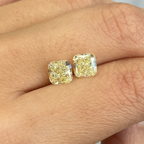 Unique matched pair of natural fancy light yellow cushion cut diamonds.