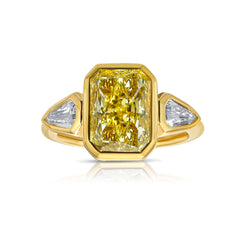 Bezel set three stone diamond ring, unique gold engagement ring, featuring a GIA certified fancy light yellow elongated radiant cut diamond.