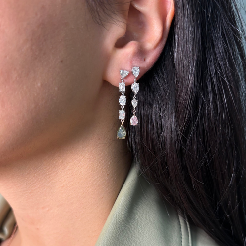 Close-up of an ear wearing a set of dangling earrings with pink diamonds