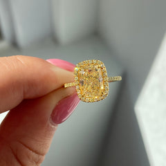 Yellow elongated cushion diamond ring surrounded by a yellow diamond halo set in yellow gold