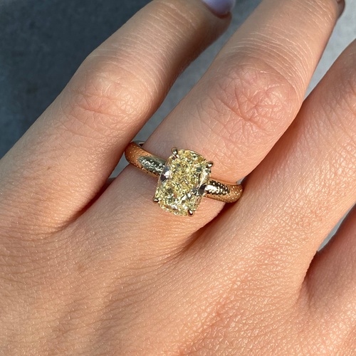 Gold ring with a yellow diamond elgated cushion 3 carat on female hand 