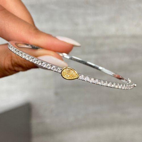 Pear shaped yellow diamond bangle with light yellow pear diamond and white round diamonds.