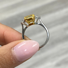 Fancy engagement ring with a yellow diamond center and two white diamonds on the sides.