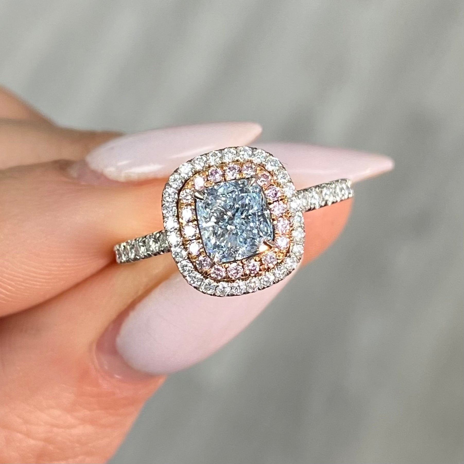 natural blue diamond ring, with blue cushion cut diamond surrounded by pink and white diamonds in a double halo ring design