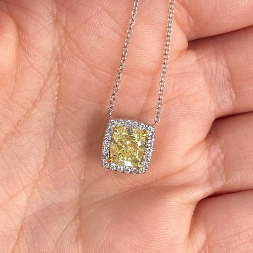 natural fancy light yellow cushion cut diamond in a white diamond halo on a 18k gold pendant