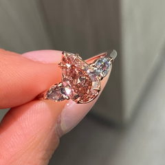 Unique three-stone ring with a deep brown-pink pear diamond and blue diamond accents, GIA certified.