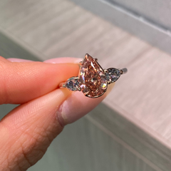 Unique three-stone ring with a deep brown-pink pear diamond and blue diamond accents, GIA certified.