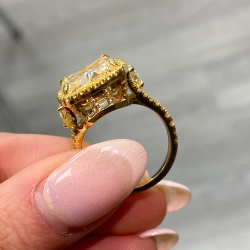 Unique light yellow cushion diamond ring with yellow diamond halo setting.