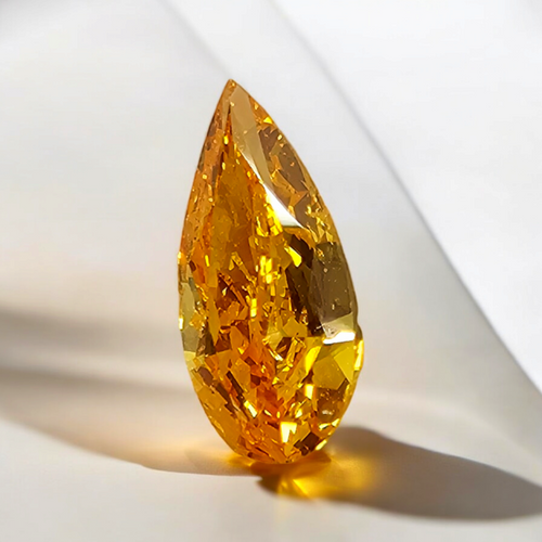 Vivid orange-yellow pear-shaped diamond with a brilliant cut, showcased on a soft, light background.