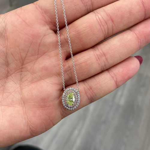 Fancy yellow-green oval diamond pendant with a double halo design and SI1 clarity.