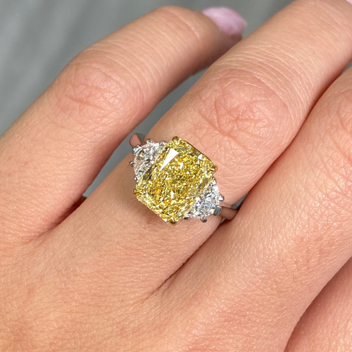 Fancy engagement ring with a yellow diamond center and two white diamonds on the sides.