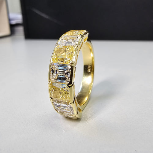 An alternating yellow diamond and white diamond half eternity band, a twist on the classic eternity with diamonds reaching only halfway across the band