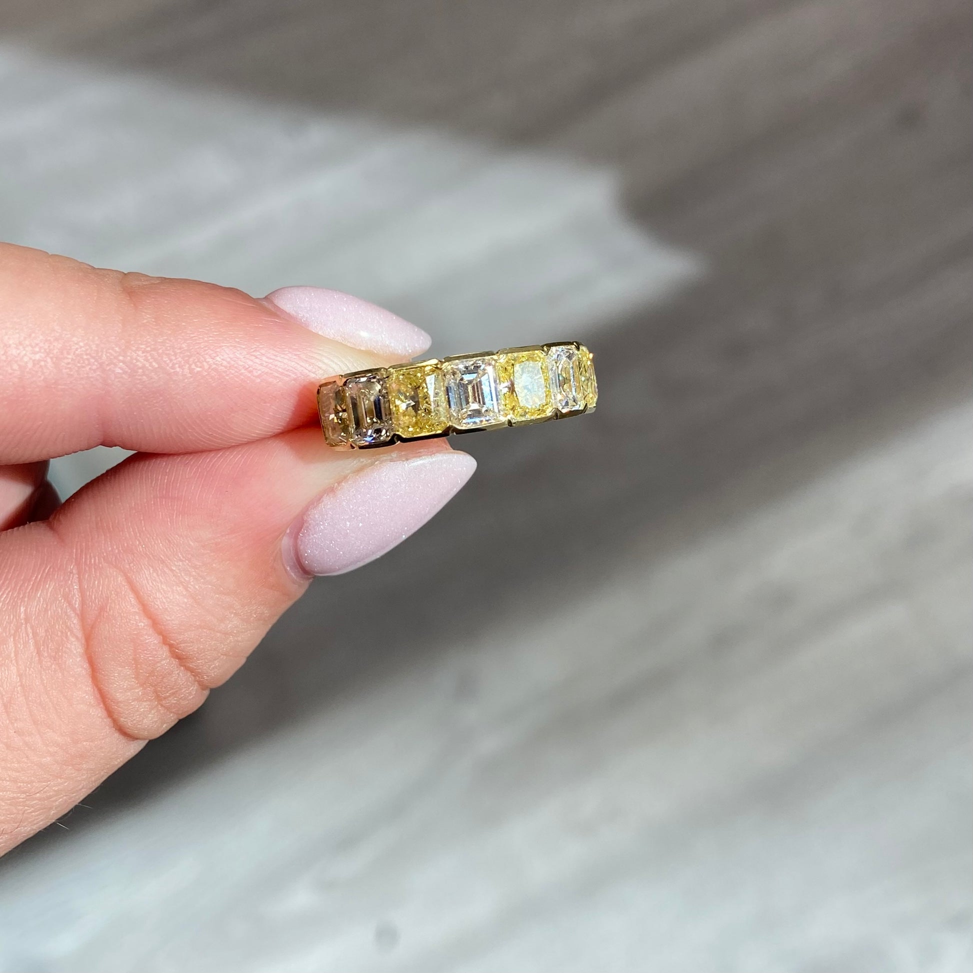 An alternating yellow diamond and white diamond half eternity band, a twist on the classic eternity with diamonds reaching only halfway across the band