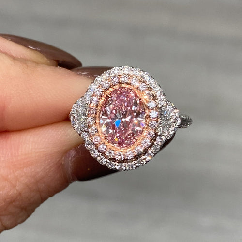 A fine pink oval diamond engagement ring with a halo of white and pink diamonds.