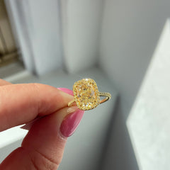 Yellow elongated cushion diamond ring surrounded by a yellow diamond halo set in yellow gold