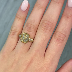 Bezel set three stone diamond ring, unique gold engagement ring, featuring a GIA certified fancy light yellow elongated radiant cut diamond