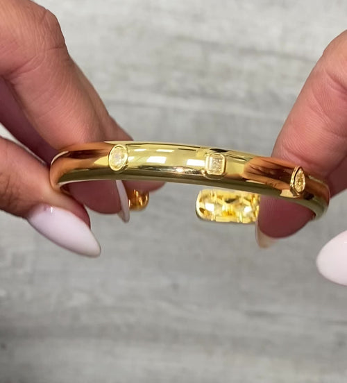 Unique bezel cuff bracelet with trio of yellow diamonds in radiant, oval, and pear shapes on a wide bangle.