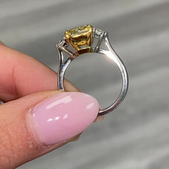 Fancy engagement ring with a yellow diamond center and two white diamonds on the sides.