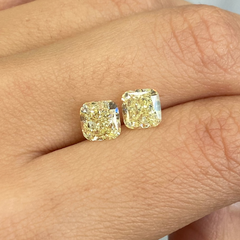 Unique matched pair of natural fancy light yellow cushion cut diamonds. 