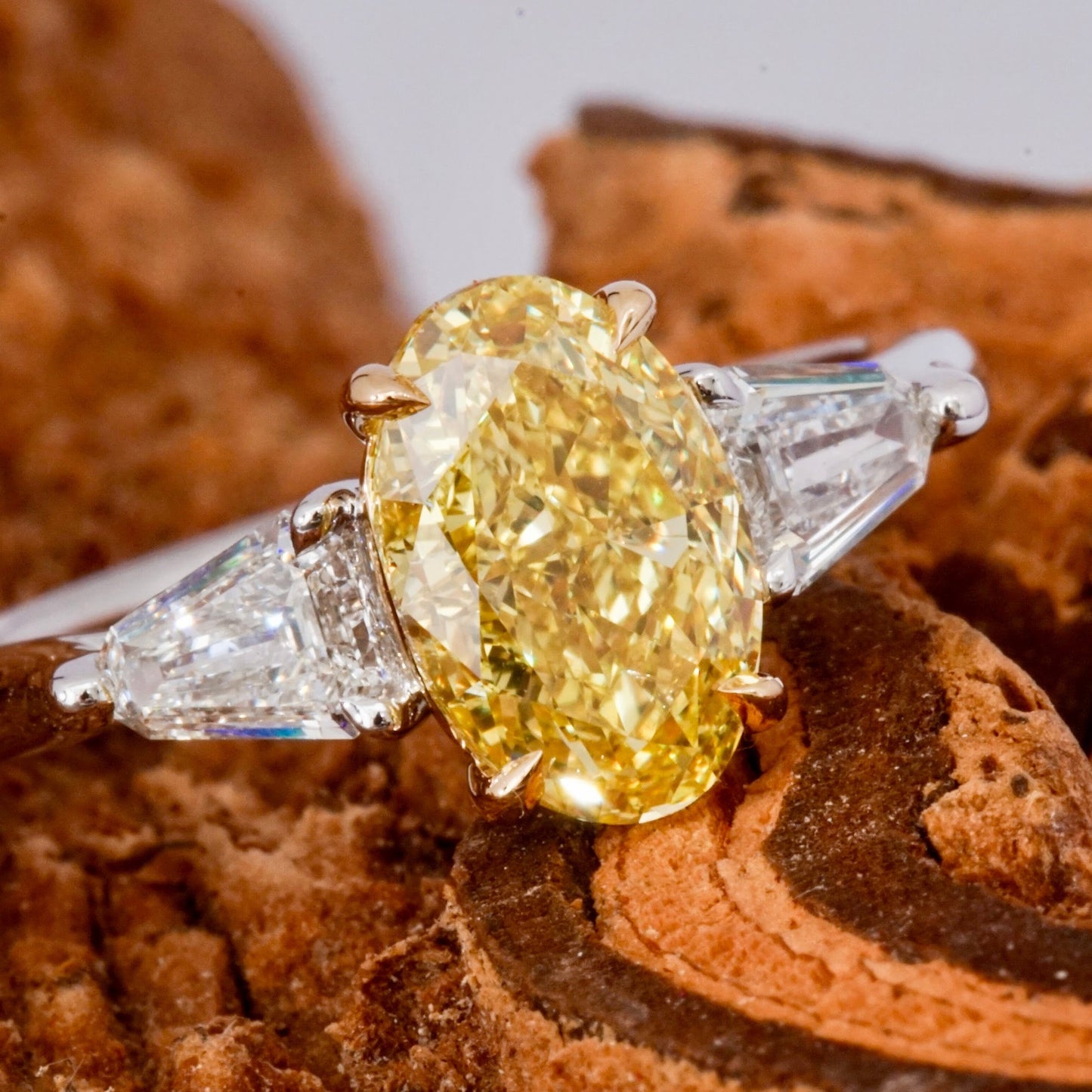 2.02ct Fancy Intense Yellow SI1 Oval, 3 stone "claw" ring with 2 whitestep cut trapezoids