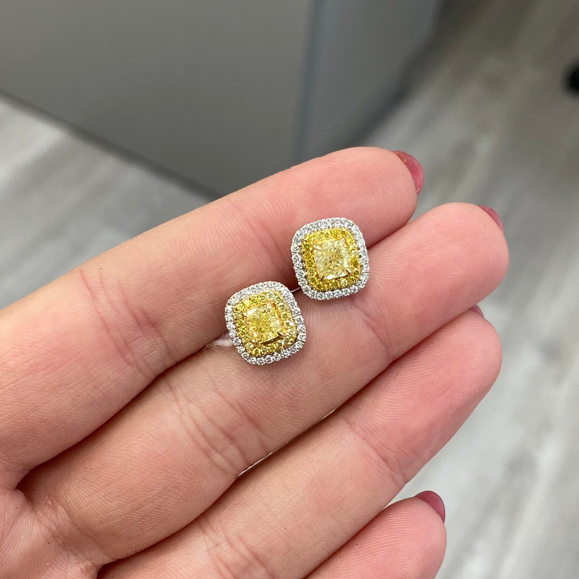 Classic diamond studs made bolder. In the center a vibrant fancy yellow cushion surrounded by a double halo. Fancy Yellow Cushion Studs 1.38 carat total diamond weight VS Clarity Center diamonds are 0.50ct each Surrounded by fancy yellow and white diamond. Set in 18k Gold